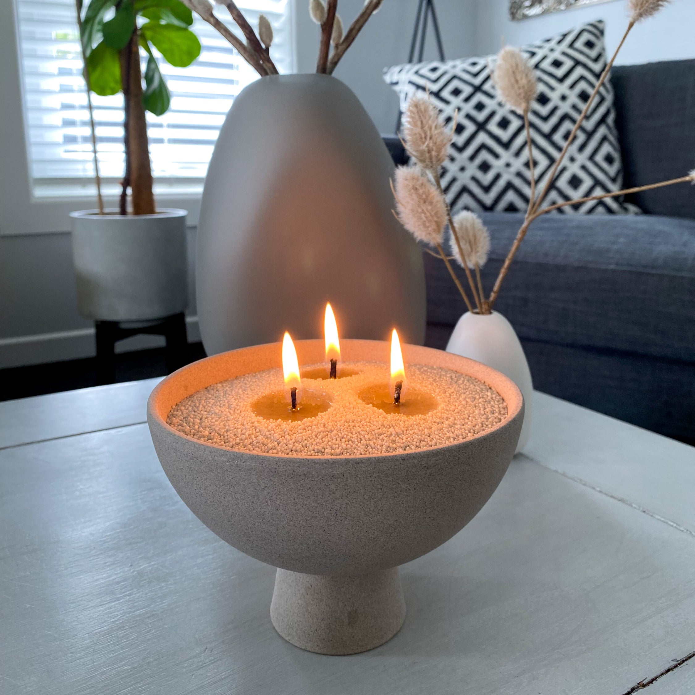 Living room centrepiece, with a three wicked sand wax candle in ceramic bowl. 