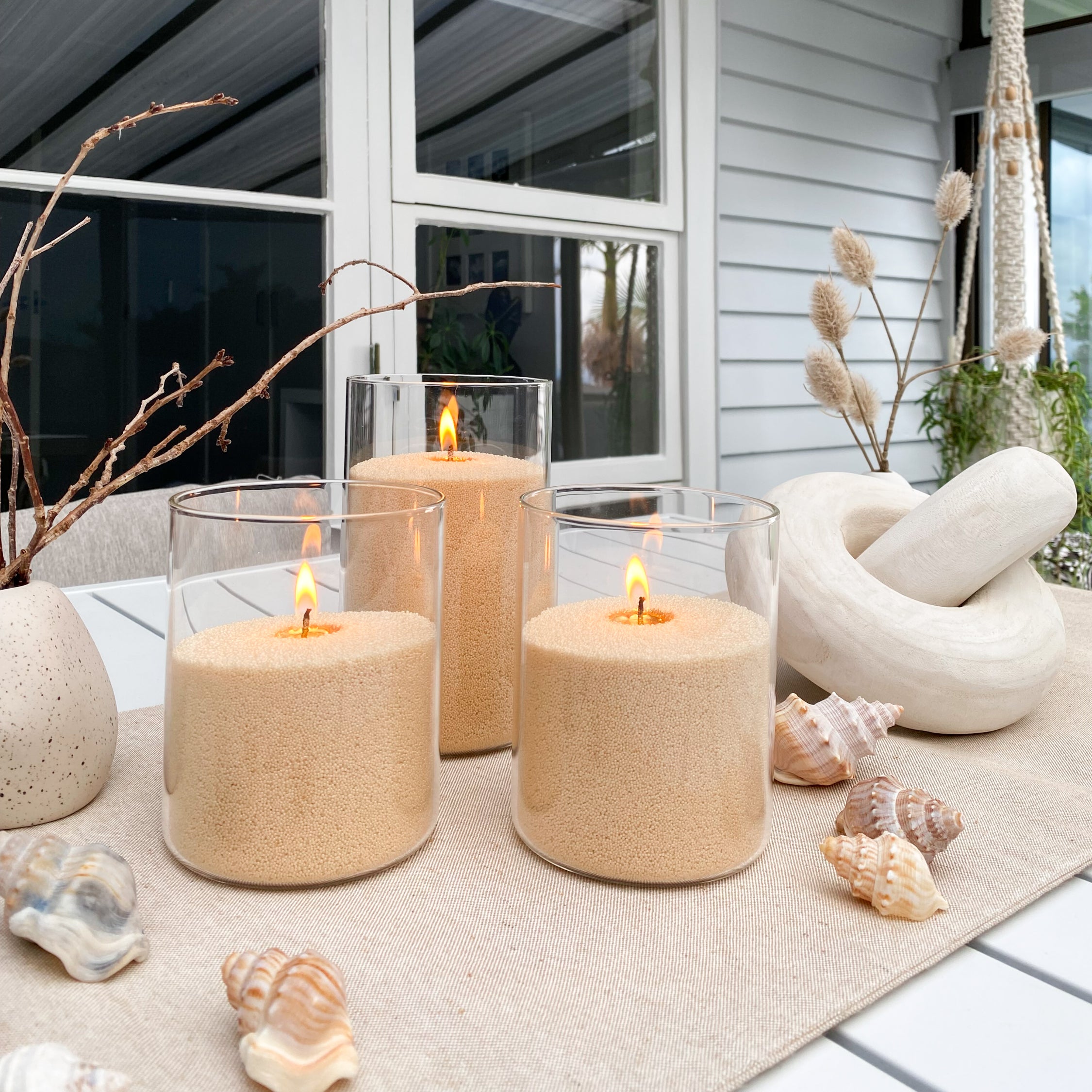 Decorative candles with gold sandwax and natural elements on a table outdoors.