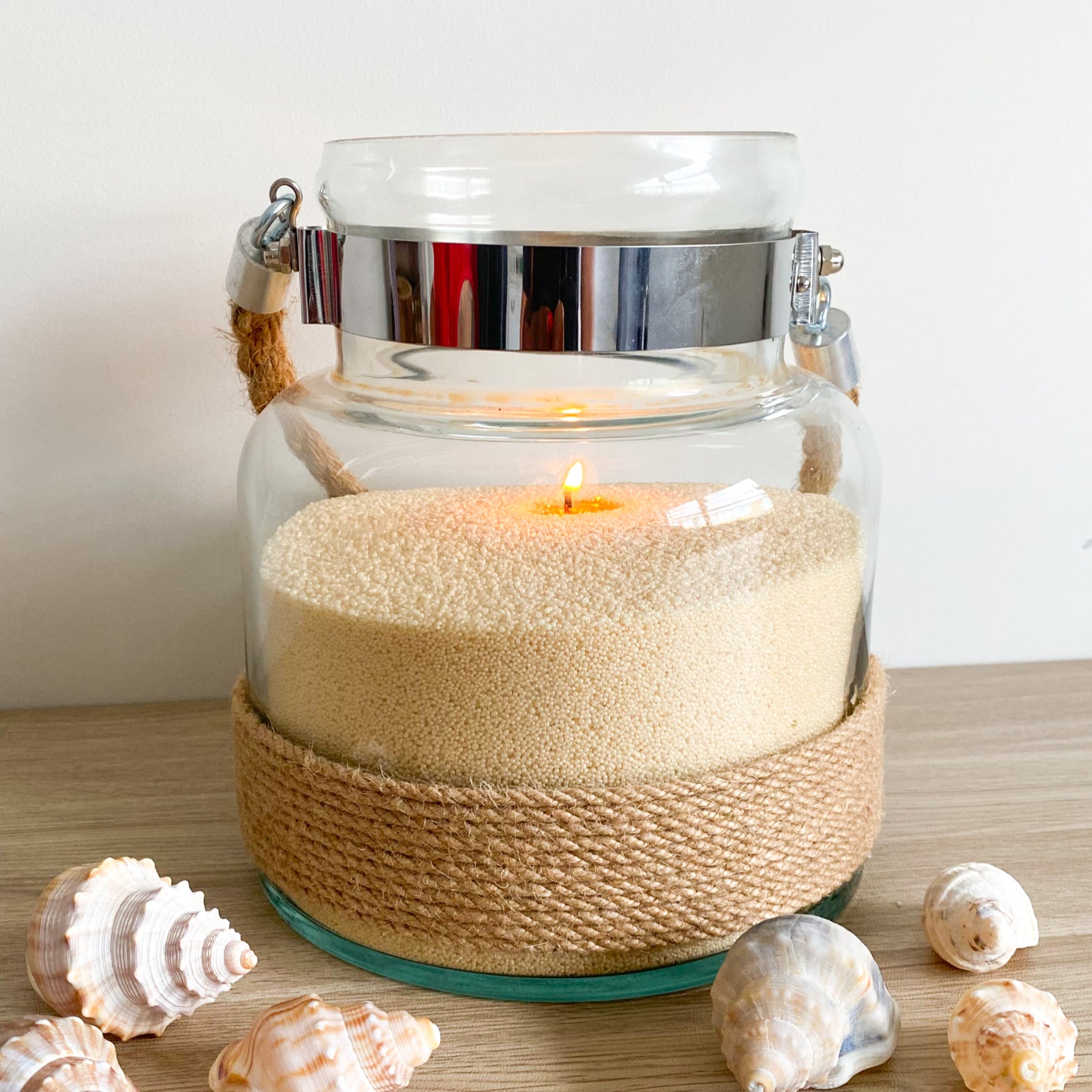 Glass candle holder filled with gold sandwax and decorative shells to elevate your office