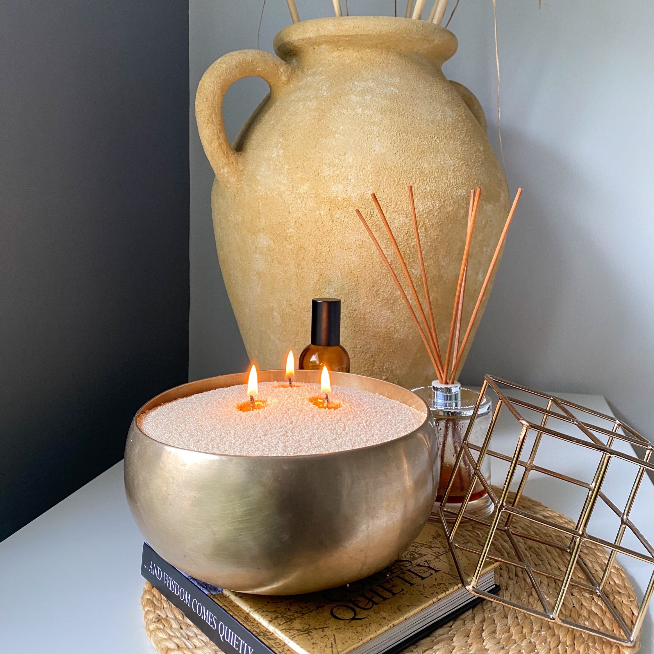 Decorative sand wax candle in a brass vessel in office room. Gold warm ambience