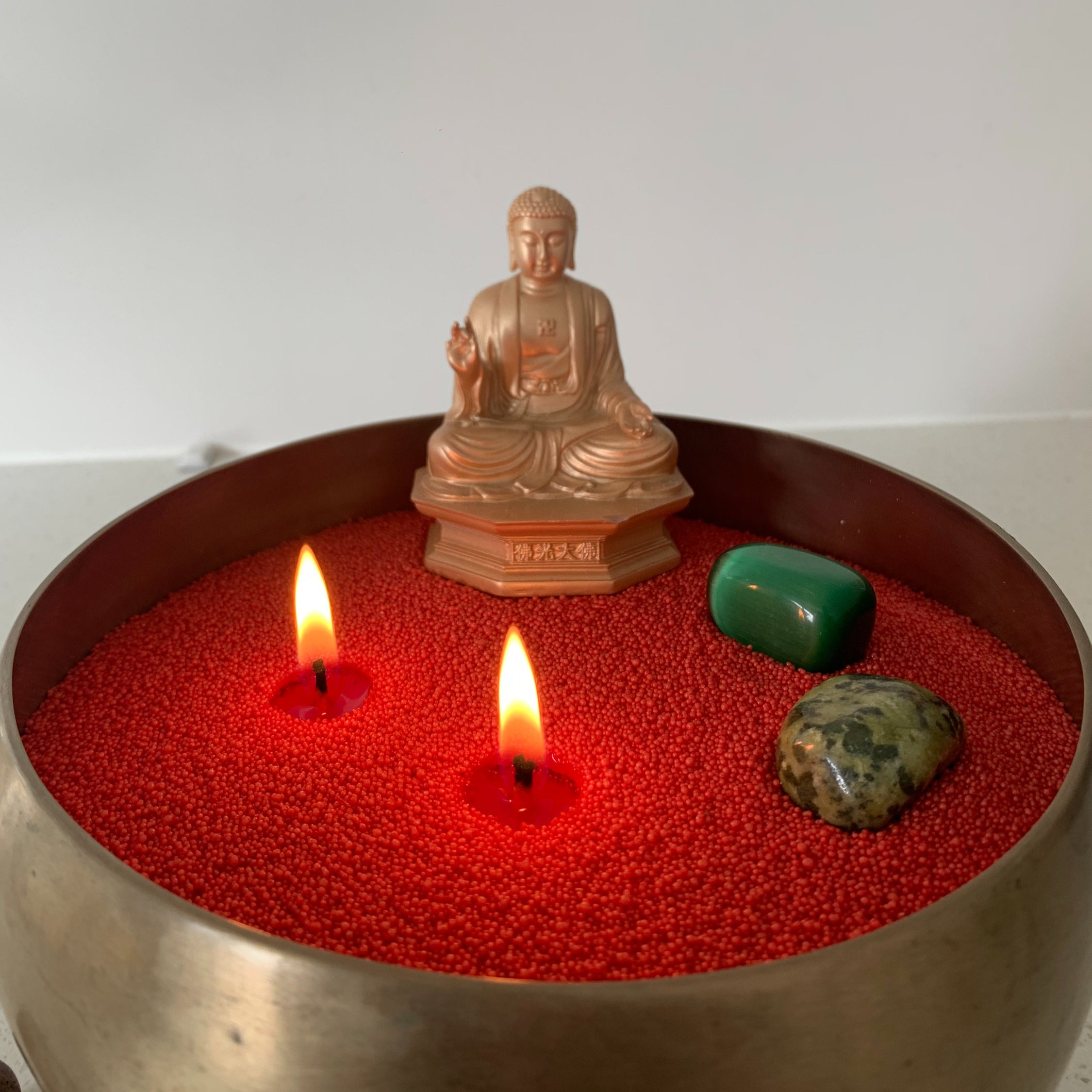 Buddha statue on a red sandwax brass vessel. Customised with two wicks and green stone. A meditative experience